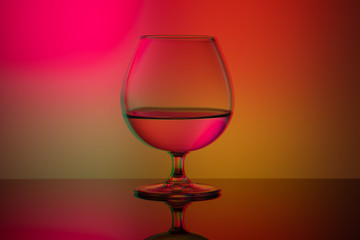 Art glitch effect, glass glass with water on a bright multi-colored background, minimalism