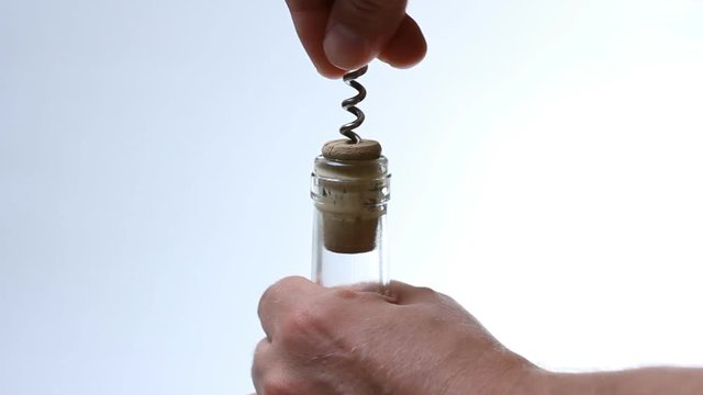 Hand with corkscrew opening a glass of wine