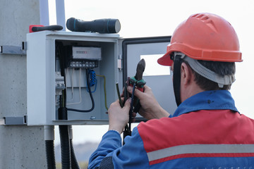 electrician engaged in the installation of electricity meter on the support of power lines . the...