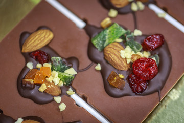 Handmade chocolate candies made from milk chocolate filled with nuts and dried fruits. Close-up