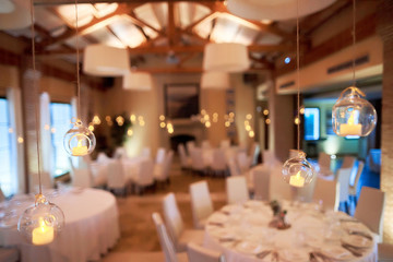 Little balls with candles hanging from from the ceiling over wedding dinner table.
