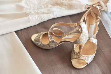 White elegant wedding dress and shoes lying on the bed.