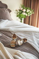 Fototapeta na wymiar White elegant wedding dress, veil and shoes lying on the bed.