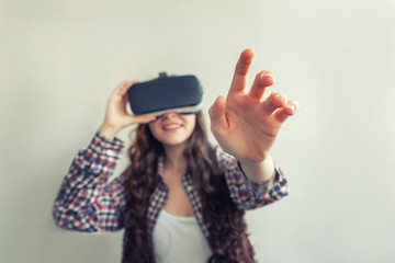 Smile young woman wearing using virtual reality VR glasses helmet headset on white background. Smartphone using with virtual reality goggles. Technology, simulation, hi-tech, videogame concept