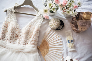Stylish white wedding bridal shoes, dress, perfume, flowers and jewelry.