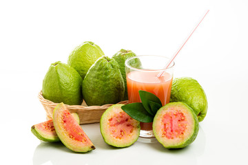A basket full of brazilian red guavas and glass with fruit juice and pieces. Copy Space.
