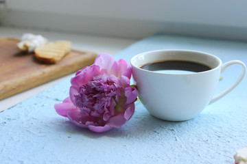 Beautiful pink peonies and a Cup of coffee on a light background. Copy space.