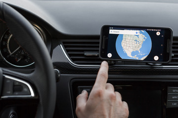 Obraz premium Close up to male driving and using navigation on the smartphone screen. Choose direction, globe on the screen.