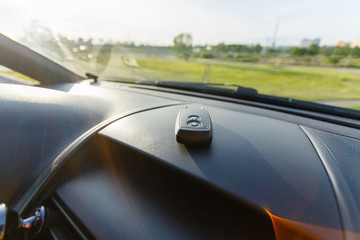 Closeup inside vehicle of wireless key ignition. Start engine key. Car key remote in black dashboard interior. Sunlight background. Modern car Interior details. Car detailing. Keys close up