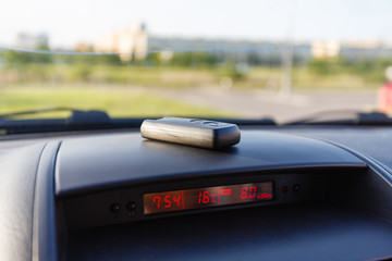 Closeup inside vehicle of wireless key ignition. Start engine key. Car key remote in black dashboard interior. Sunlight background. Modern car Interior details. Car detailing. Keys close up