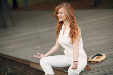 Portrait of young positive woman with curly hair meditating in park