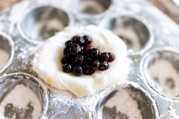 Piece of mochi sticky glutinous rice cake dusted with starch flour to make dessert in muffin pan tin with heart blueberry berry fruit filling