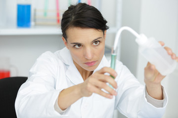 Fototapeta premium woman scientist adding liquid to test tube