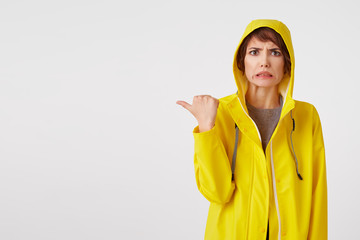 Young attractive girl in a yellow raincoat with a disgusted expression on her face wants to draw...