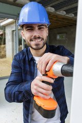 worker smiling and holding a drill outdoors