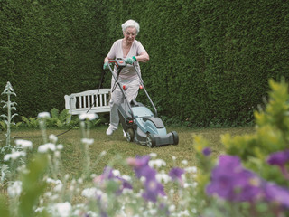 Senior woman working with mower in the garden