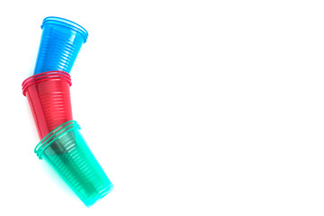 Bright colourful disposable plastic cups isolated on white. Ecology problem. Background and free space for design or text, top view.