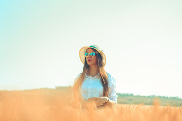 Abeautiful young woman standing in a wheat field in a sunny day