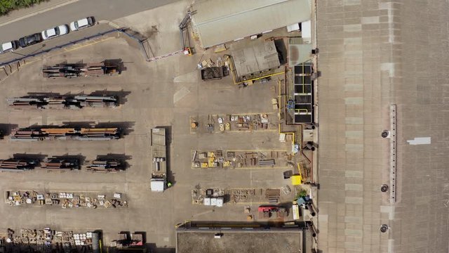 4K aerial footage over a factory warehouse in the North of England that's storing freshly created steel about to be loaded onto a lorry