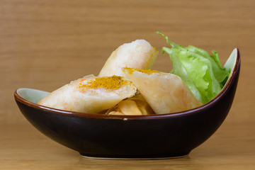 Harumaki, fried rolls in batter with shrimp pulp, flavoured with paprika, served with green salad on a boat-shaped plate