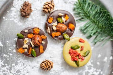Christmas theme. Handmade chocolates candy. Mini chocolate dessert covered with nuts and dried fruits. Garland lamps bokeh on background. Copy space