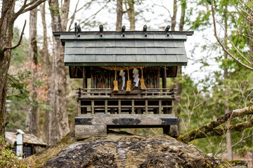 Small wooden shinto shrine in forest in Takayama Hida no Sato folk village in Gifu prefecture, Japan