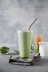Green matcha tea and milk in latte glass on grey table. Space for text.
