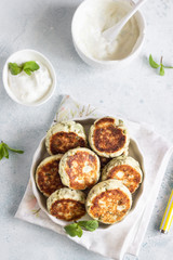 Cottage cheese fritters (syrniki) with green pea, dill, mint and sauce. Light stone background. Healthy breakfast or diet lunch. Copy space.