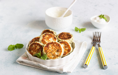 Cottage cheese fritters (syrniki) with green pea, dill, mint and sauce. Light stone background. Healthy breakfast or diet lunch. Copy space.
