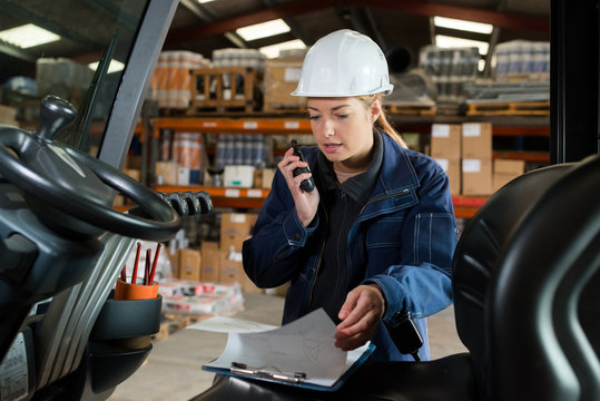 lady talking into walkie talkie while driving forklift