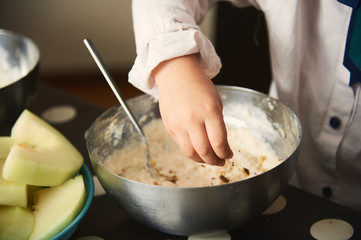 Child cook prepares cottage cheese dessert with nuts. Hands close up.