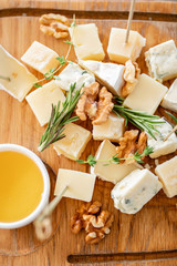 Cheese plate. Delicious cheese mix with walnuts, honey on wooden table. Tasting dish on a wooden plate. Food for wine. Buffet at the gala dinner.