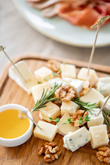 Cheese plate. Delicious cheese mix with walnuts, honey on wooden table. Tasting dish on a wooden plate. Food for wine. Buffet at the gala dinner.