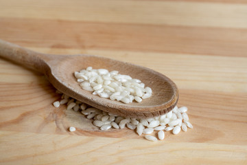 Rice on wooden spoon on wooden background. Concept of cooking and food
