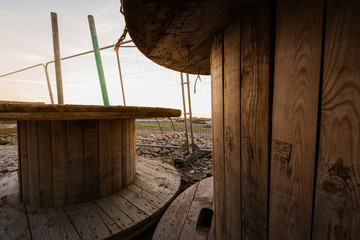 Large empty Wooden Coil - Wooden Spool - Wooden Bobbins in a construction yard against a bright sunset