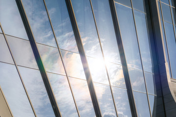 closeup of a modern window glass building with sun and blue sky reflecting in it