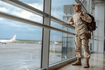 Full length of American soldier in camouflage looking at window
