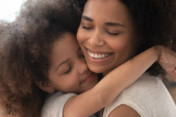 Happy affectionate african family mom and little child daughter embrace