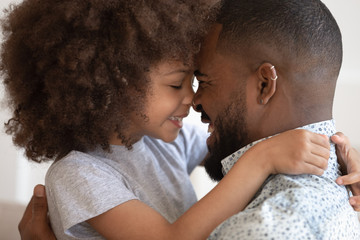 Cute little african daughter embrace touch noses with happy dad