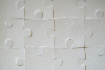 Multiple white puzzle pieces put together. View from above.