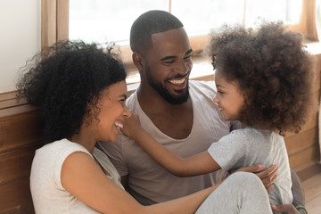 Obraz premium Happy black family bonding laughing sit on bedroom floor