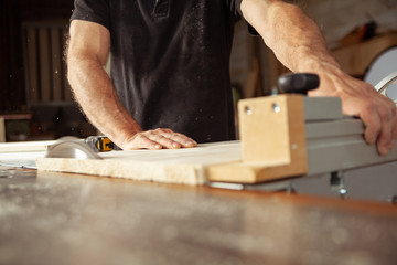 Carpenter working with a bench saw cutting planks