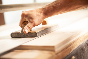 Carpenter using sander in workshop to smooth wood