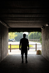 Young man standing in a subway tunnel of a concrete building