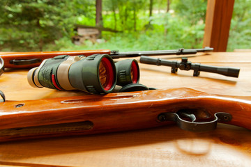 Binoculars laying on top of a rifle on a table