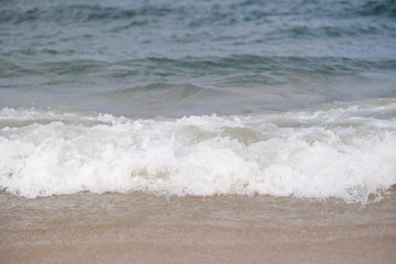 closeup on waves hitting the beach on a sunny summer day