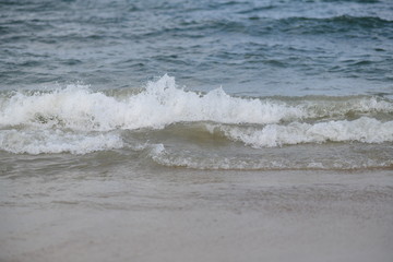 closeup on waves hitting the beach on a sunny summer day