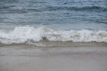 closeup on waves hitting the beach on a sunny summer day