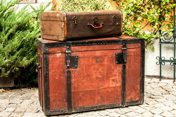 Old retro wooden chest and vintage grunge suitcase isolated on stone paved house backyard