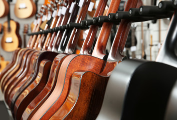 Row of different guitars in music store, closeup